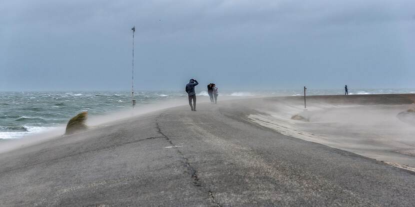 Mensen lopen op het strand in een storm